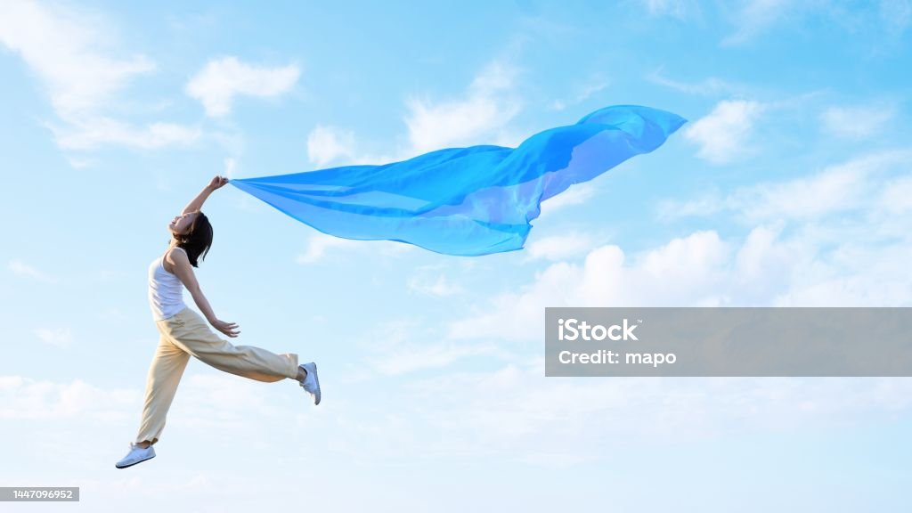 A woman flapping her wings and lightly flying in the sky Women Stock Photo