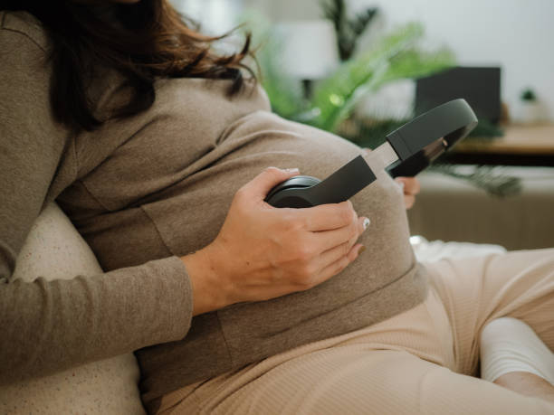 Asian pregnant woman is sitting in bedroom. Happy pregnant mother touching abdomen and waiting her baby or fetus, give birth soon. Delayed gratification stock pictures, royalty-free photos & images