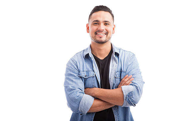 Latin young man in a studio Handsome young Hispanic guy smiling with his arms crossed against a white background Happy people stock pictures, royalty-free photos & images