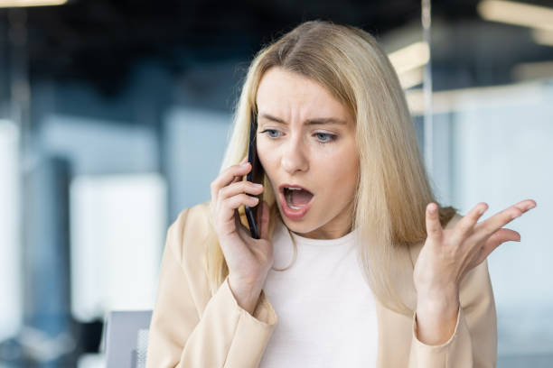 Concerned businesswoman talking on phone in office stock photo